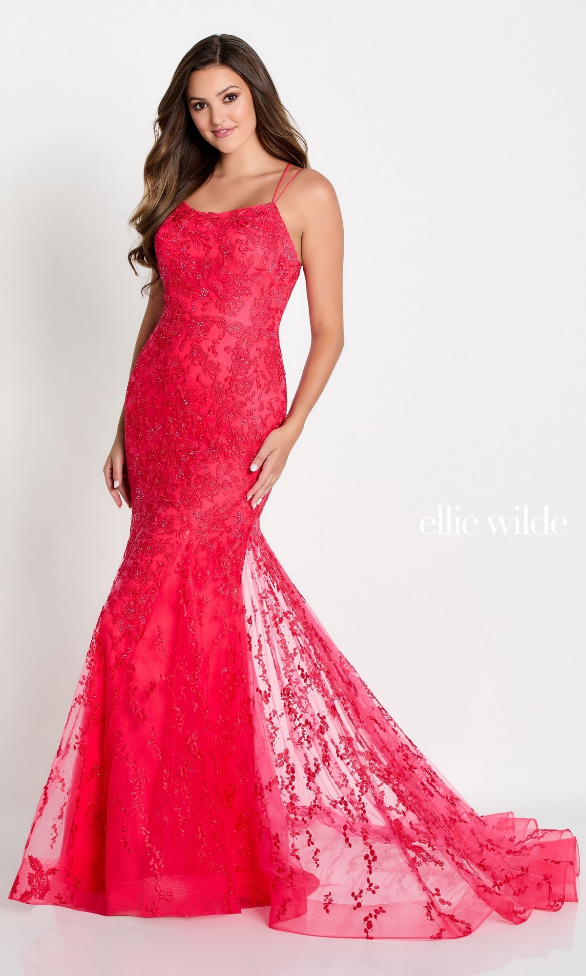 A woman stands against a white background wearing the Long Lace Mermaid Prom Dress with a strappy back by Ellie Wilde, featuring a fitted silhouette and sequin embellishments. The